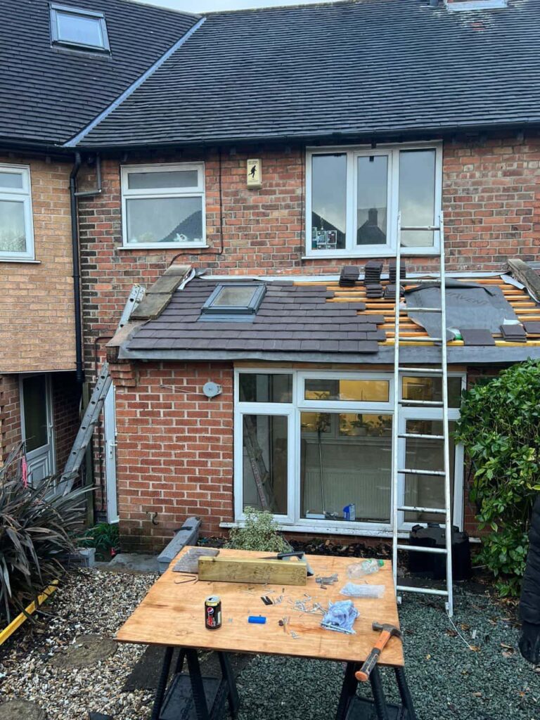 This is a photo of a roof extension that is having new roof tiles installed. This is a photo taken from the roof ridge looking down a tiled pitched roof on to a flat roof. Works carried out by Branston Roofing Repairs