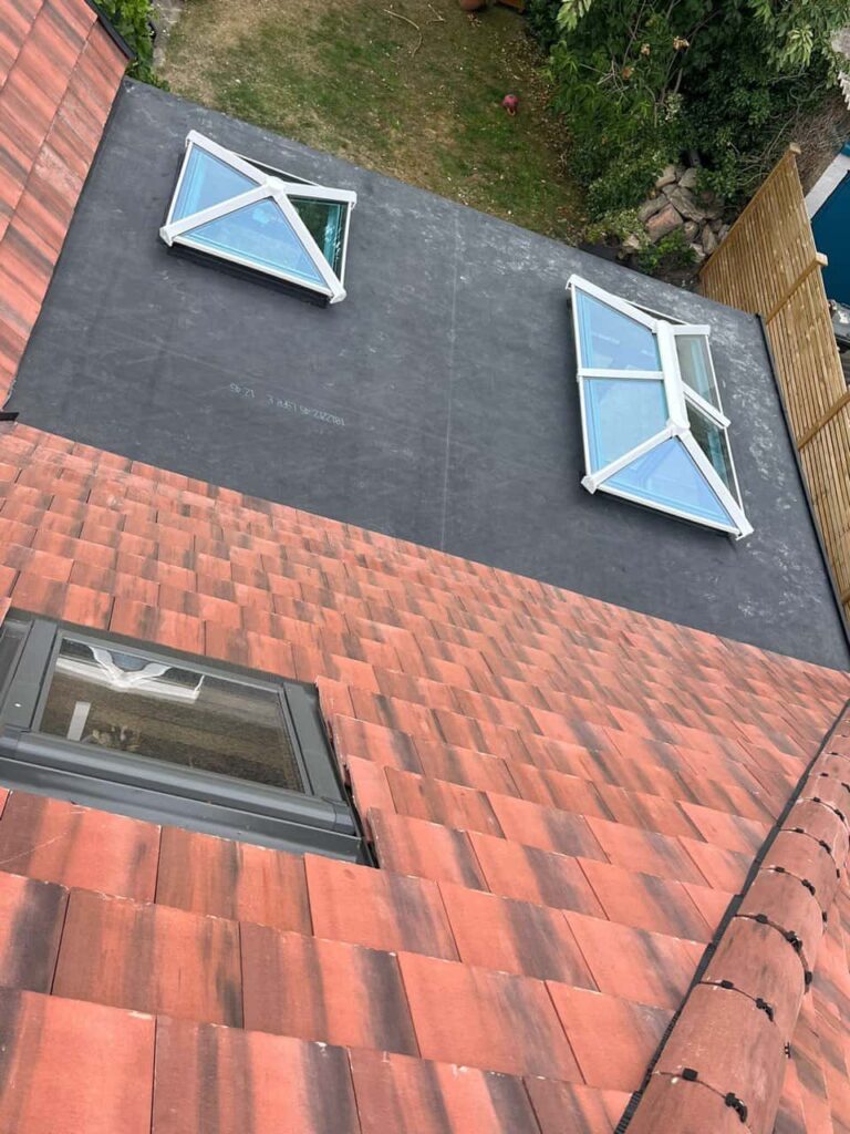 This is a photo taken from the roof ridge looking down a tiled pitched roof on to a flat roof. Works carried out by Branston Roofing Repairs